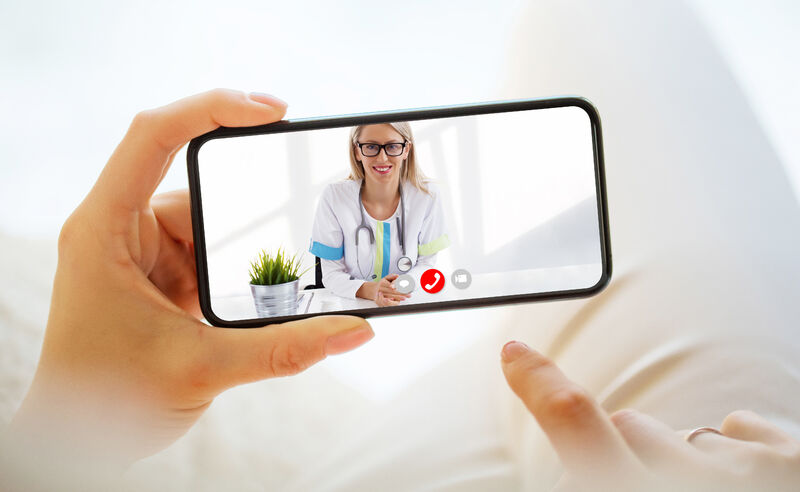 Hand holding moible phone with doctor on screen